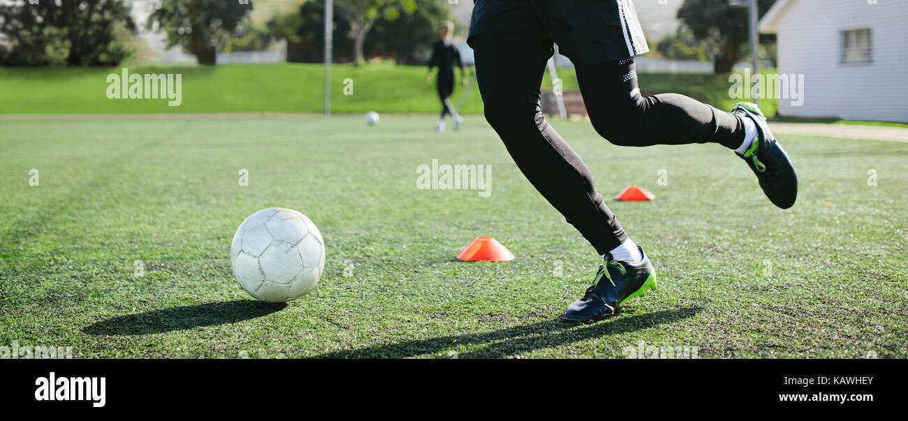 Bein skill Training am Fußballplatz. Low Angle View der Jungen Fußball-Spieler läuft im Fußball Feld führenden Ball zwischen Reihe von Kegeln während praktisch Stockfoto