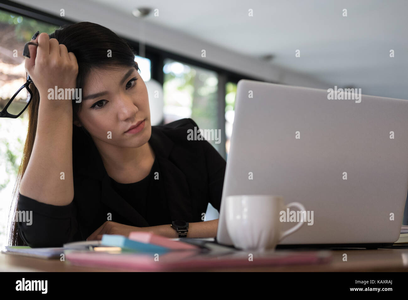 Müde Geschäftsfrau mit der Hand auf den Kopf am Büro. Frustrierte junge Frau mit Kopfschmerzen am Arbeitsplatz. erschöpft weiblichen Startup in Depressionen nach langen Stockfoto