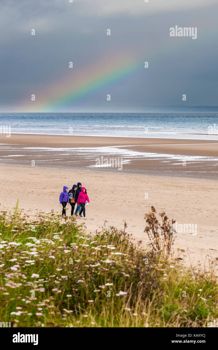 Familie, die einen Sonntagnachmittagspaziergang in Anoraks am West Sands Strand neben den Golfplätzen in St Andrews, Fife, Schottland, Großbritannien, macht Stockfoto
