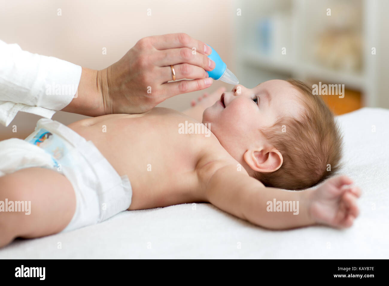 Frau Hand reinigt Babys Nase mit Staubsauger Stockfoto