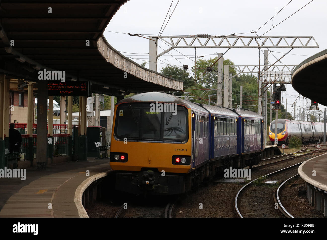 Klasse 144 Pacer dmu in Carnforth Station wartet der West Coast Main Line mit einem nördlichen Service nach einem Jungfrau pendolino nach Norden verläuft. Stockfoto