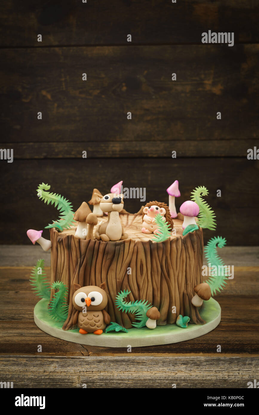 Verzauberten Wald Wald themed Fondant Kuchen mit einem Igel, Rehe, Owl, Baumstamm, Farne, Pilze und Blätter auf Holz- Hintergrund mit Copyspace Stockfoto