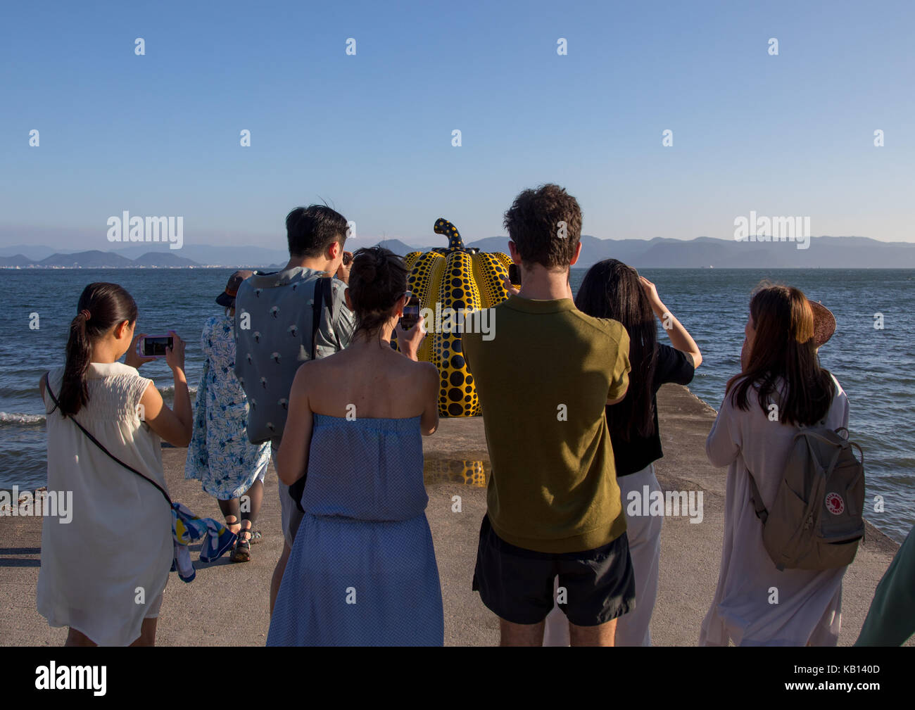 Touristen, die Bilder von den gelben Kürbis von Yayoi Kusama auf Pier am Meer, Seto Binnenmeer, Naoshima, Japan Stockfoto