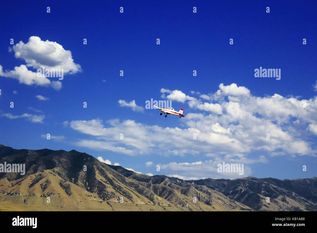 Einen kleinen roten und weißen Flugzeug in der Nähe von Utah Bergen auf einen strahlend blauen Himmel fliegen. Stockfoto