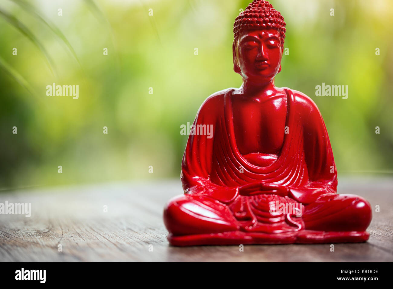 Red Buddha Figur über grüner Hintergrund Stockfoto