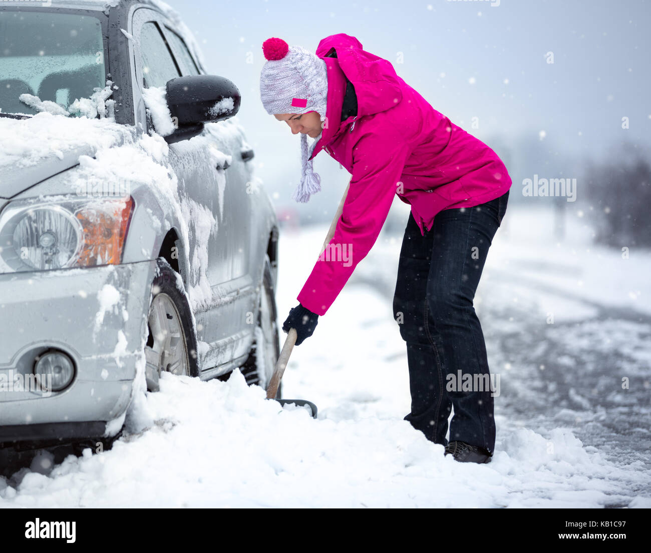 Frau räumt mit einem Besen Schnee aus einem Auto 4543491 Stock