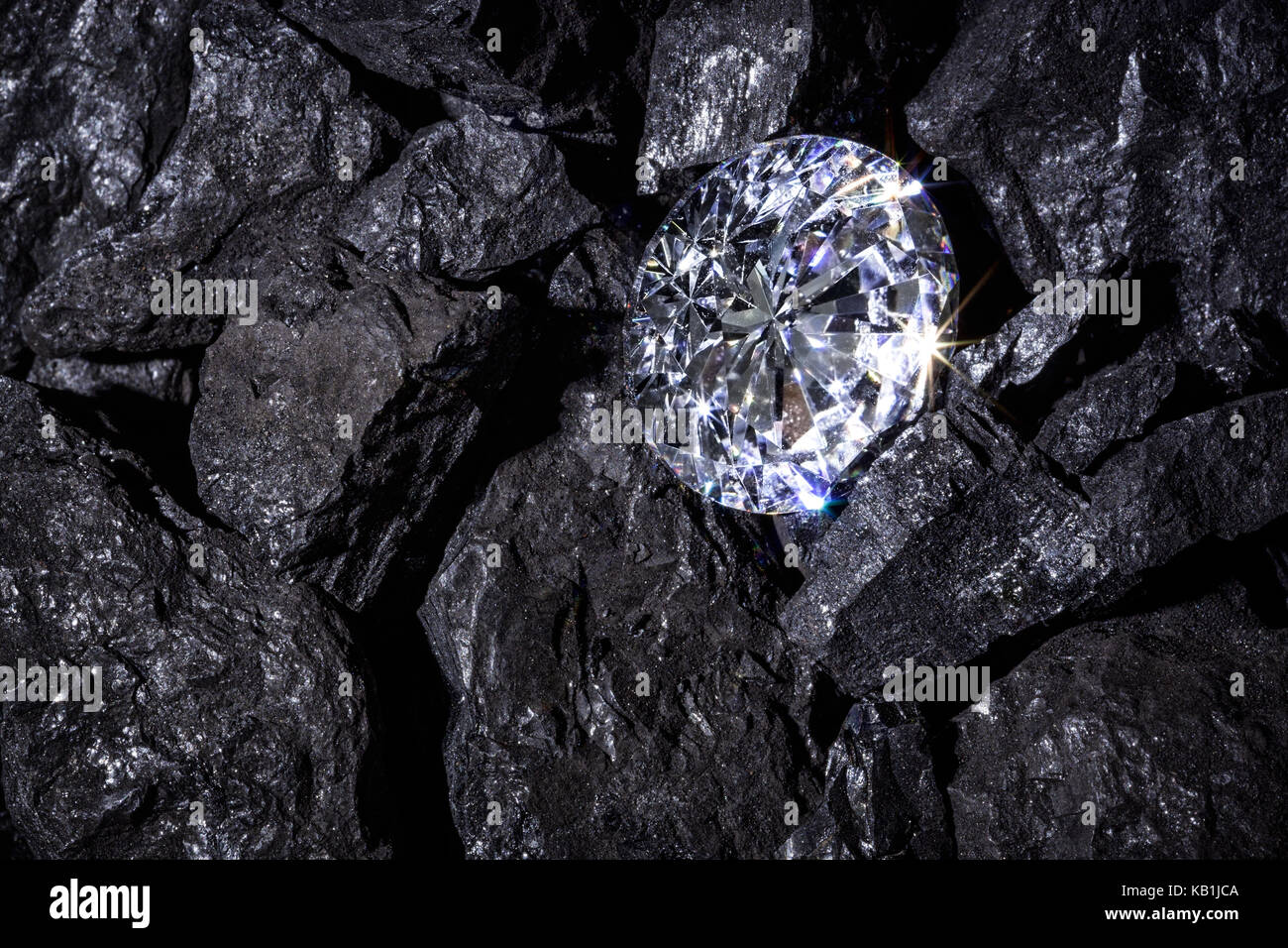 Eine einzelne solitaire Diamant unter einigen schwarzen Teile von Kohle. Stockfoto