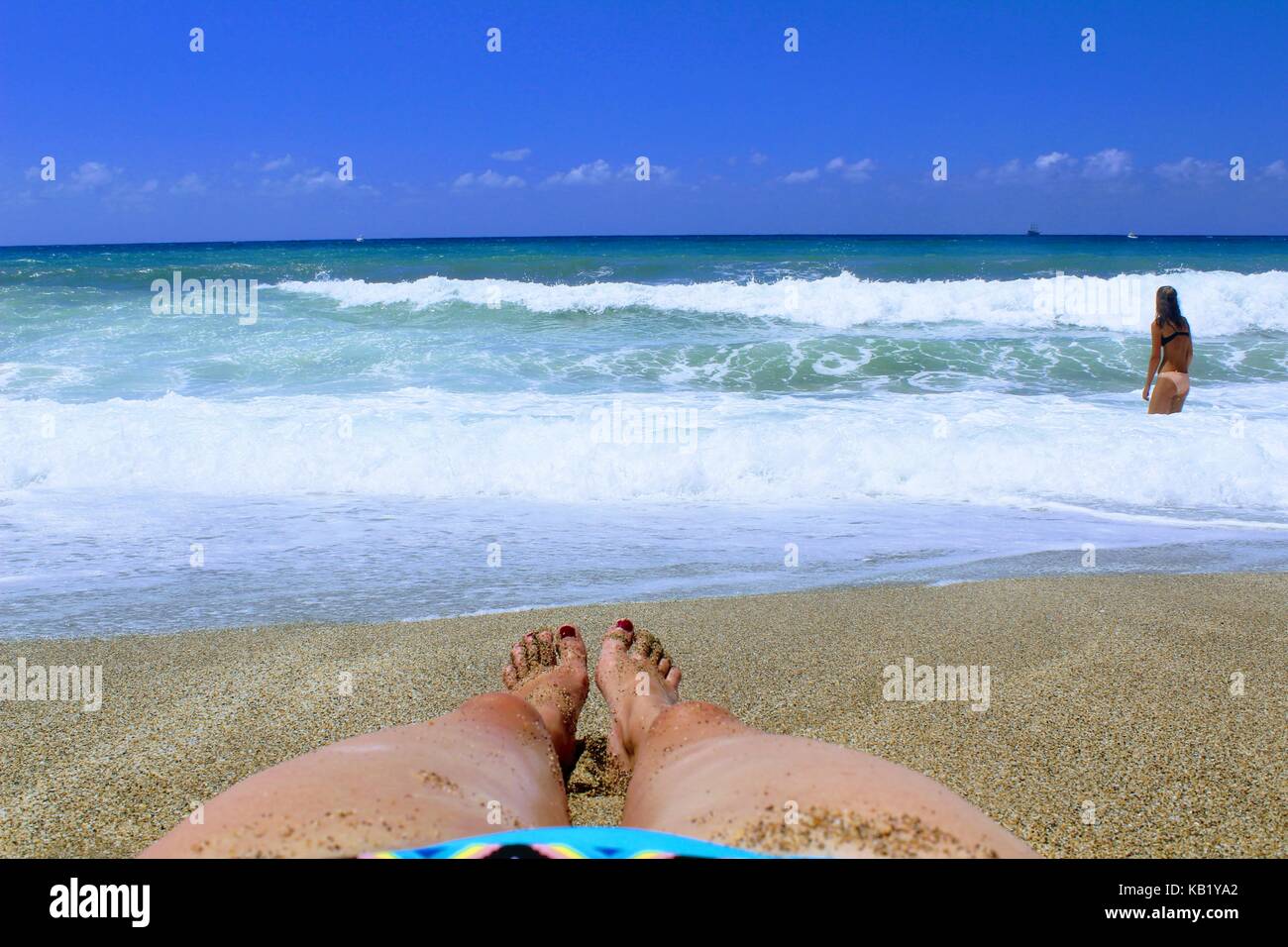 Weibliche Füße liegen auf dem Sand in der Surf Zone. Stockfoto
