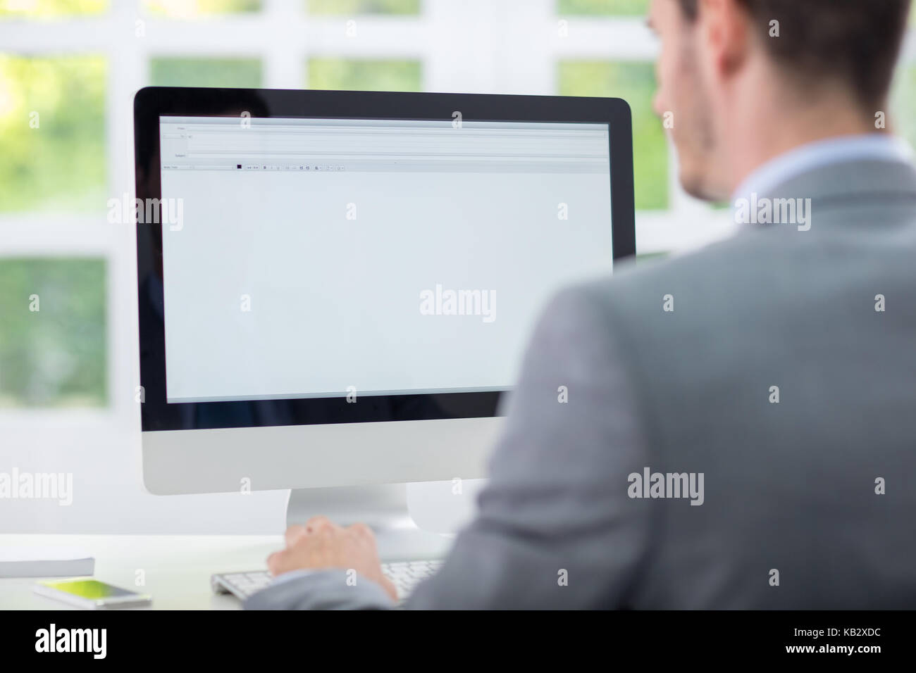 Business Mann sitzt vor dem leeren Monitor, Rückansicht Stockfoto