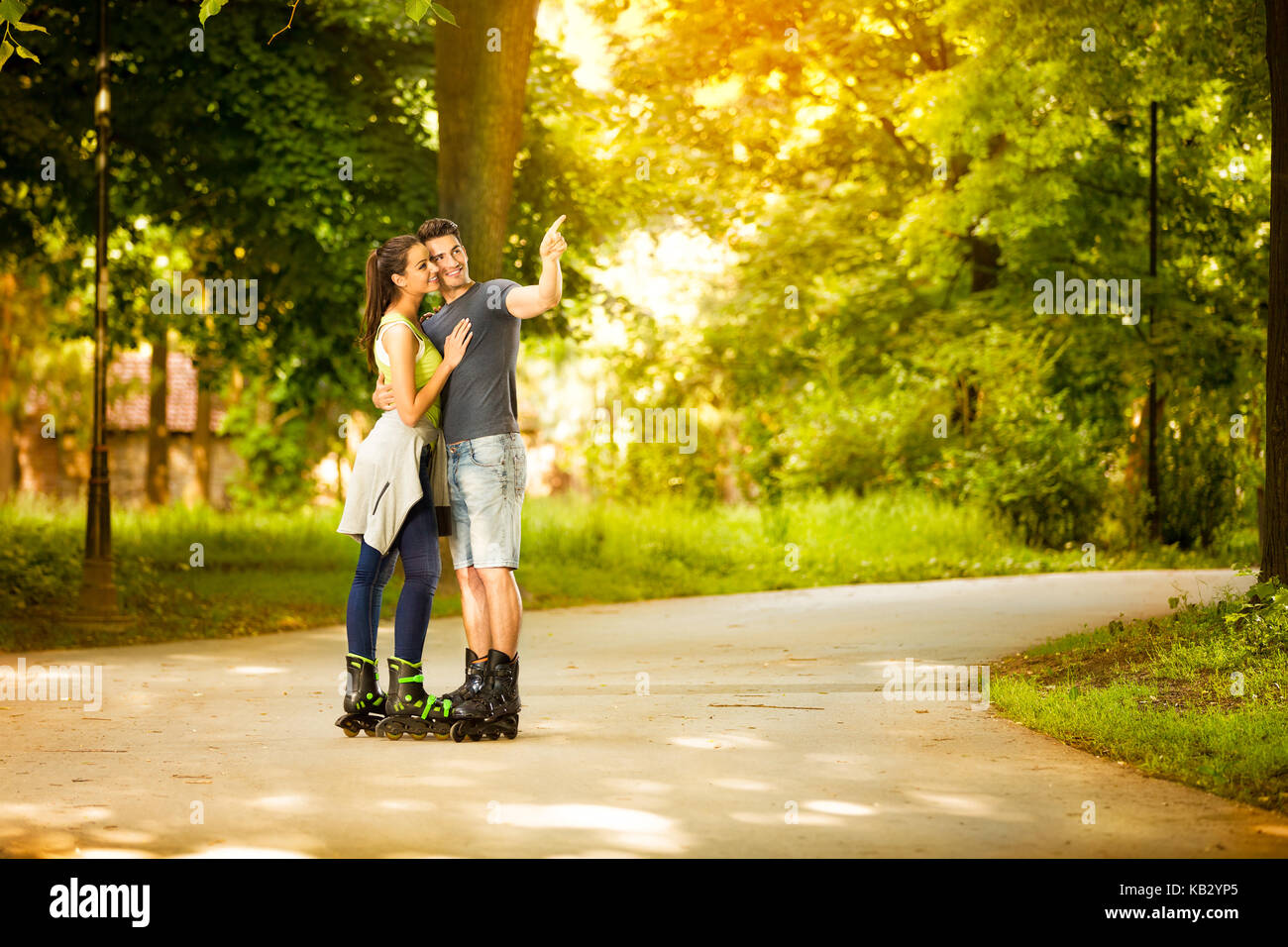 Liebe junge Paar auf Inline-skates, junger Mann zeigte mit dem Finger Stockfoto