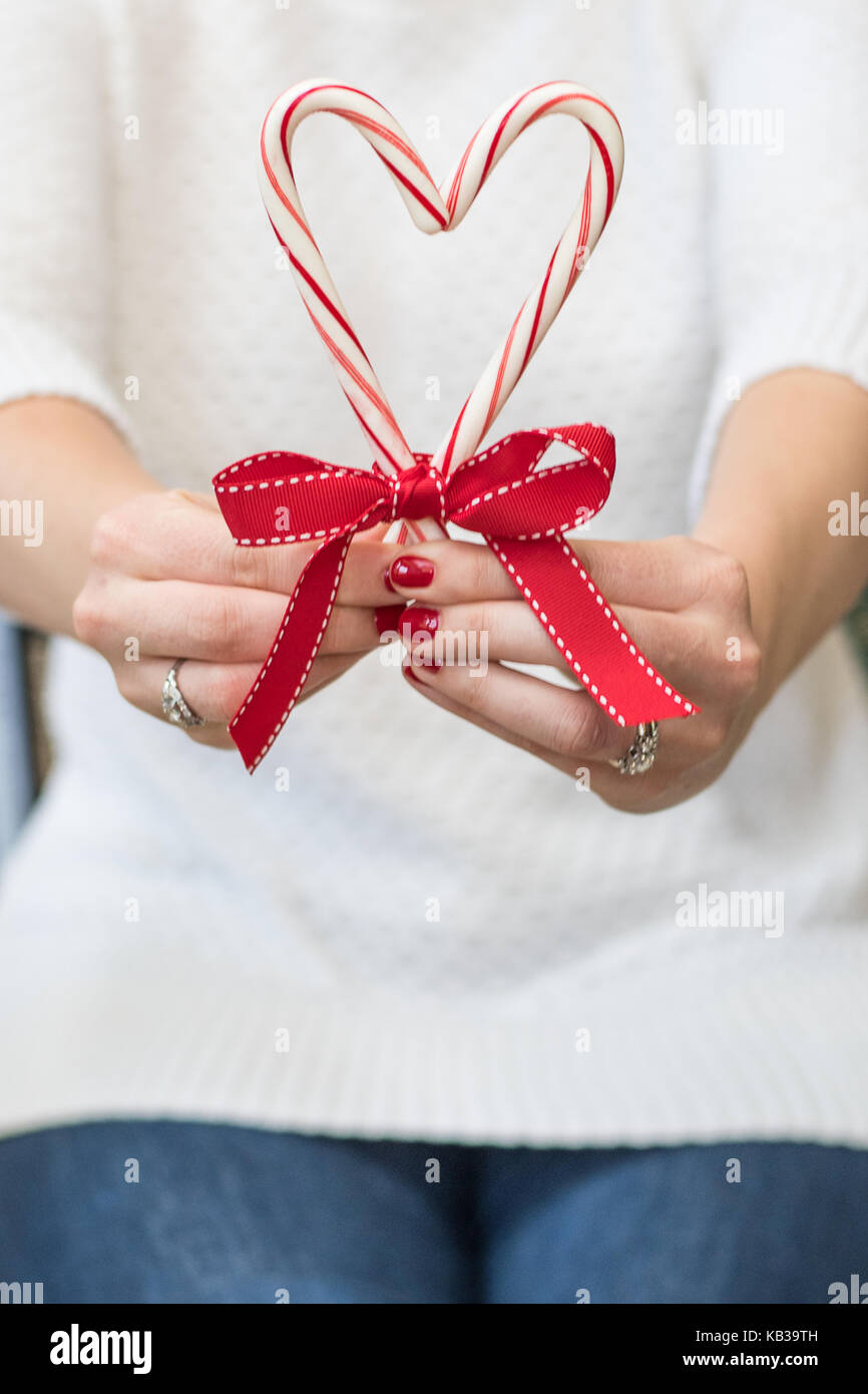 Frau mit frohe Weihnachten Zuckerstangen und einen roten Bogen in einem weißen Pullover vor einem Hintergrund mit Raum für Kopie Stockfoto