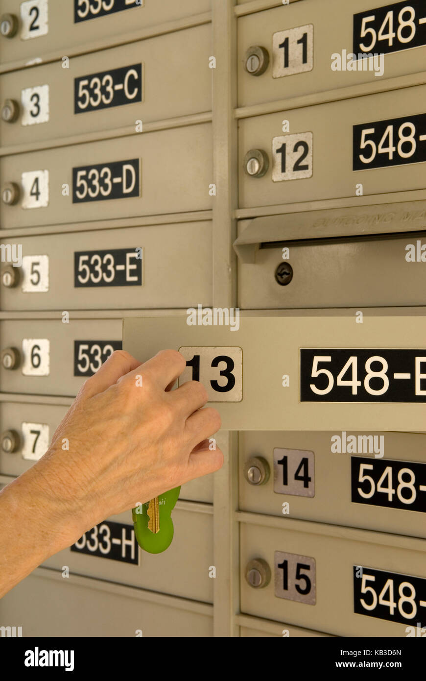 Kaukasische ältere Frau (Alter 60-70), die Briefkasten mit Schlüssel für einen Apartment-Komplex öffnet, USA Stockfoto