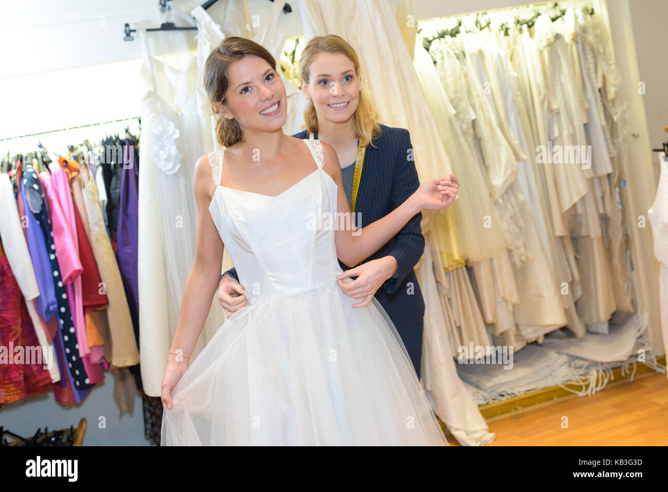Frauen, die versuchen, auf Hochzeit Kleid mit schneiderin Stockfoto