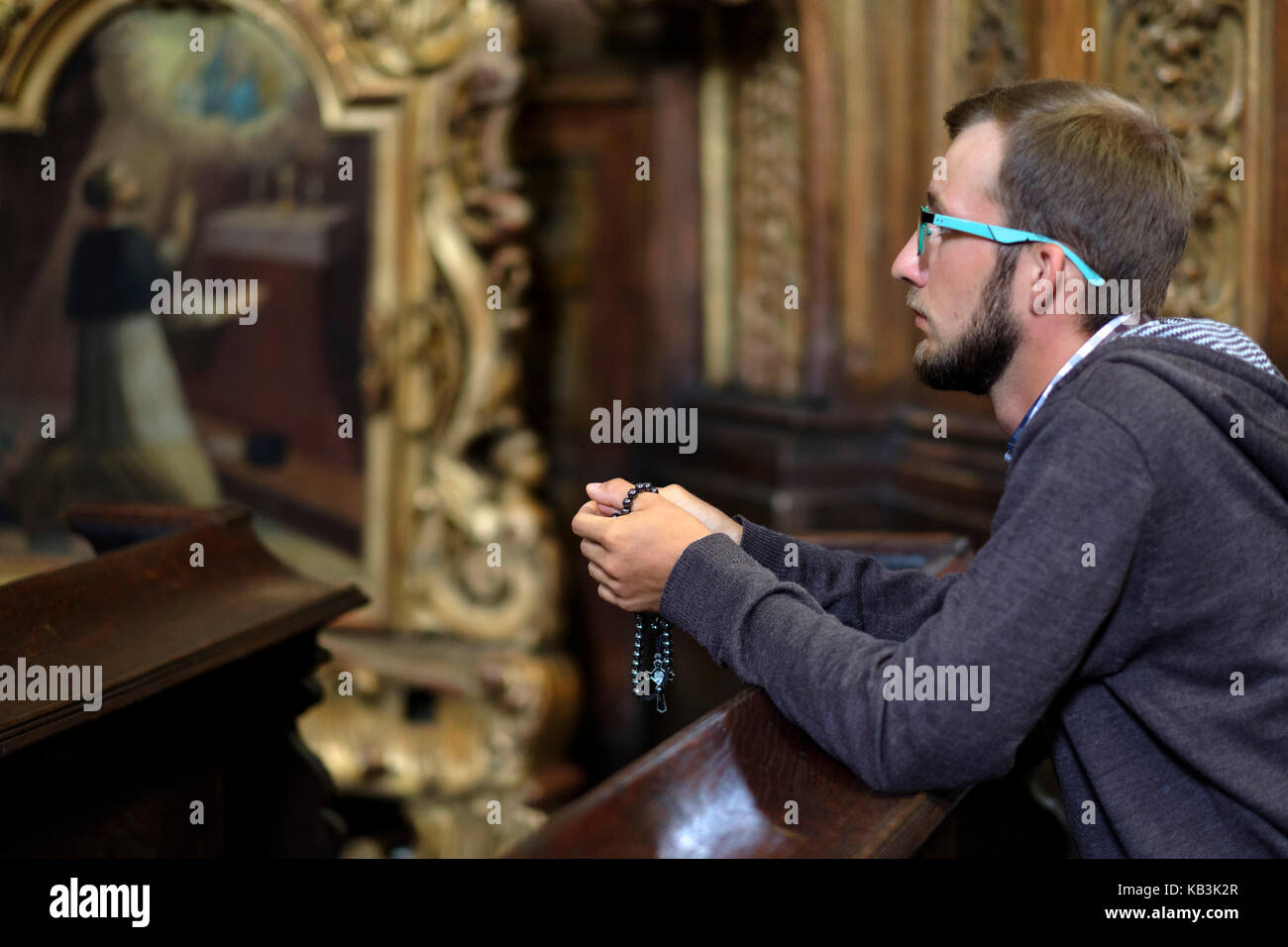 Junger Mann mit Brille und Bart in einer Kirche beten Stockfoto