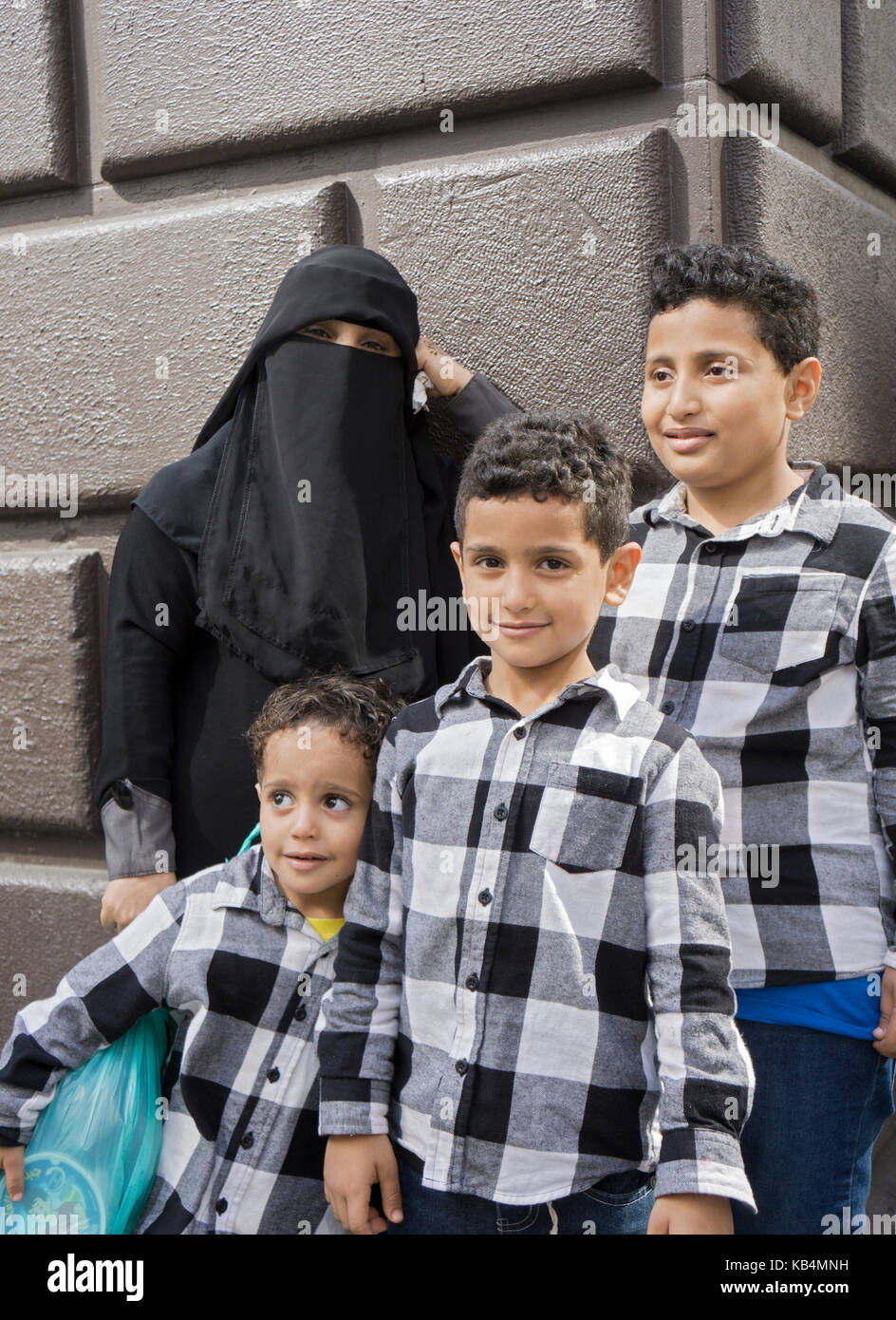 Eine Frau aus dem Jemen und ihre drei Söhne tragen identische Shirts auf er Muslimische Day Parade in Midtown Manhattan, New York City. Stockfoto