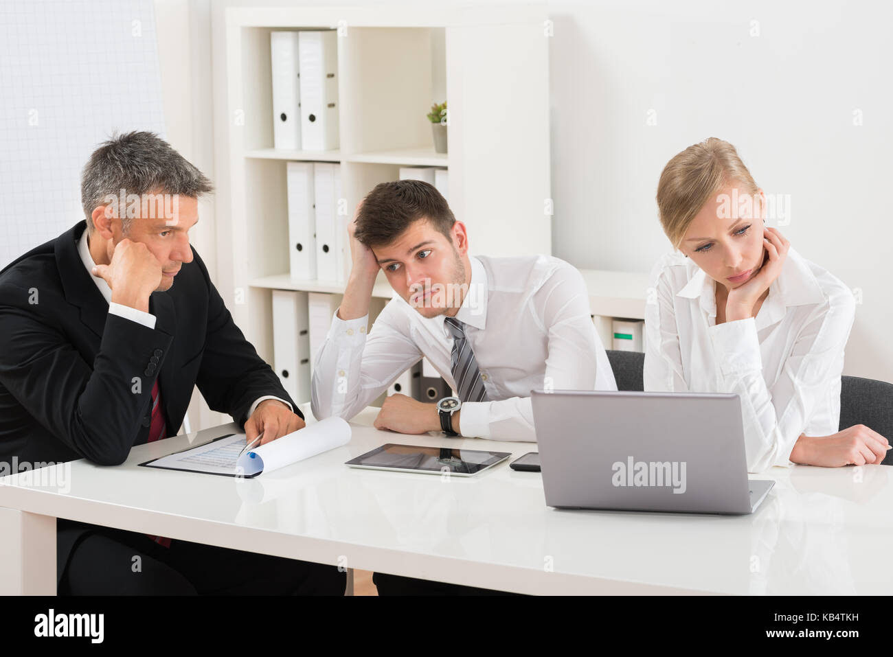 Gruppe von Geschäftsleuten Gelangweilt Sitzen am Schreibtisch im Büro Stockfoto