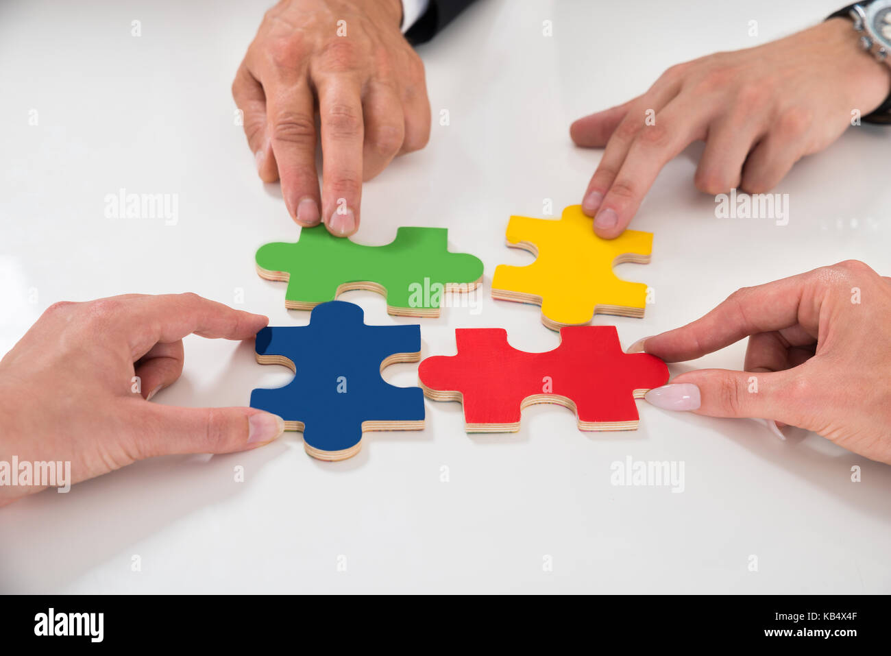 Close-up von Menschen Montage bunte Puzzleteile am Schreibtisch Stockfoto