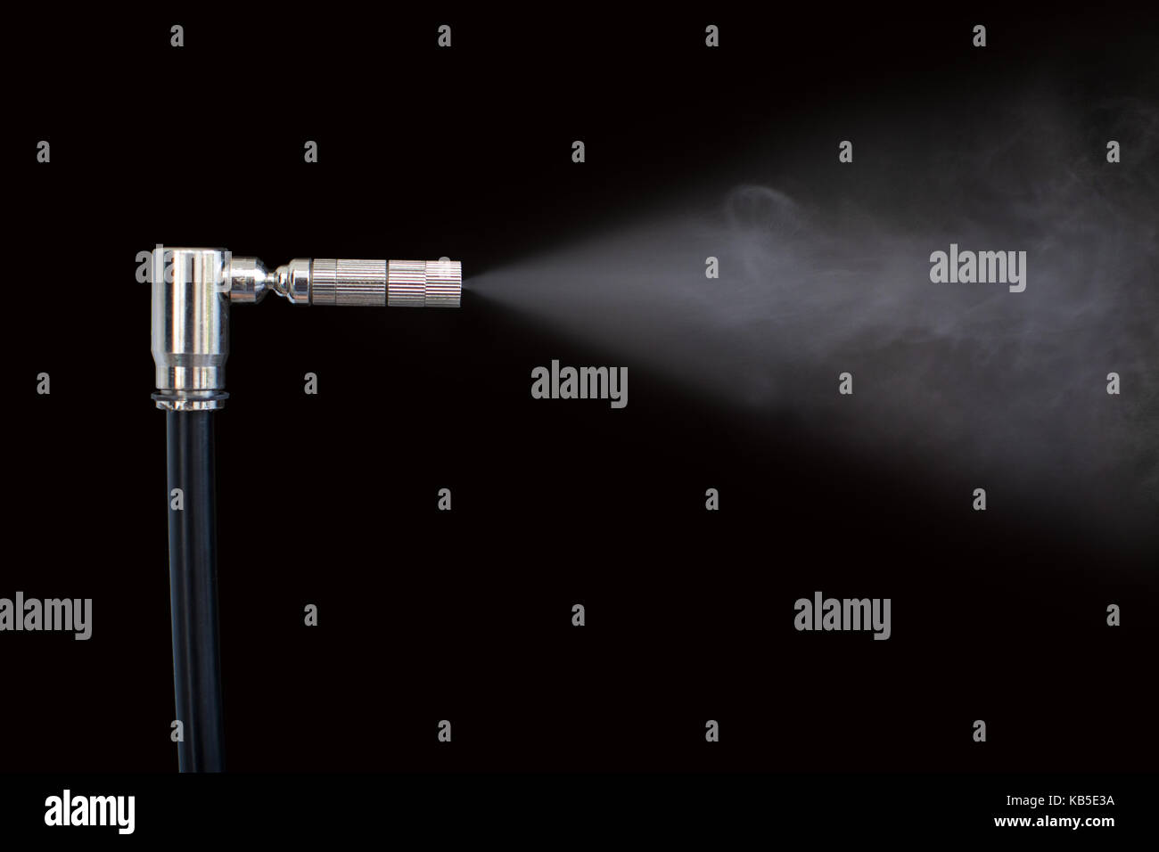 Düse spritzt Flüssigkeit in Dampf schwarzer Hintergrund Stockfoto