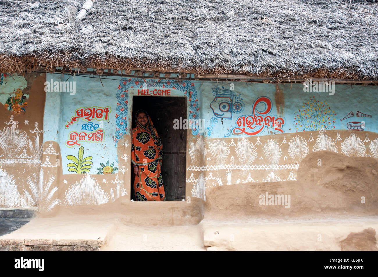 Frau an der Tür der traditionellen Mud walled Odisha Haus im Dorf mit traditionellen Mustern verziert, Dandasahi, Odisha, Indien Stockfoto