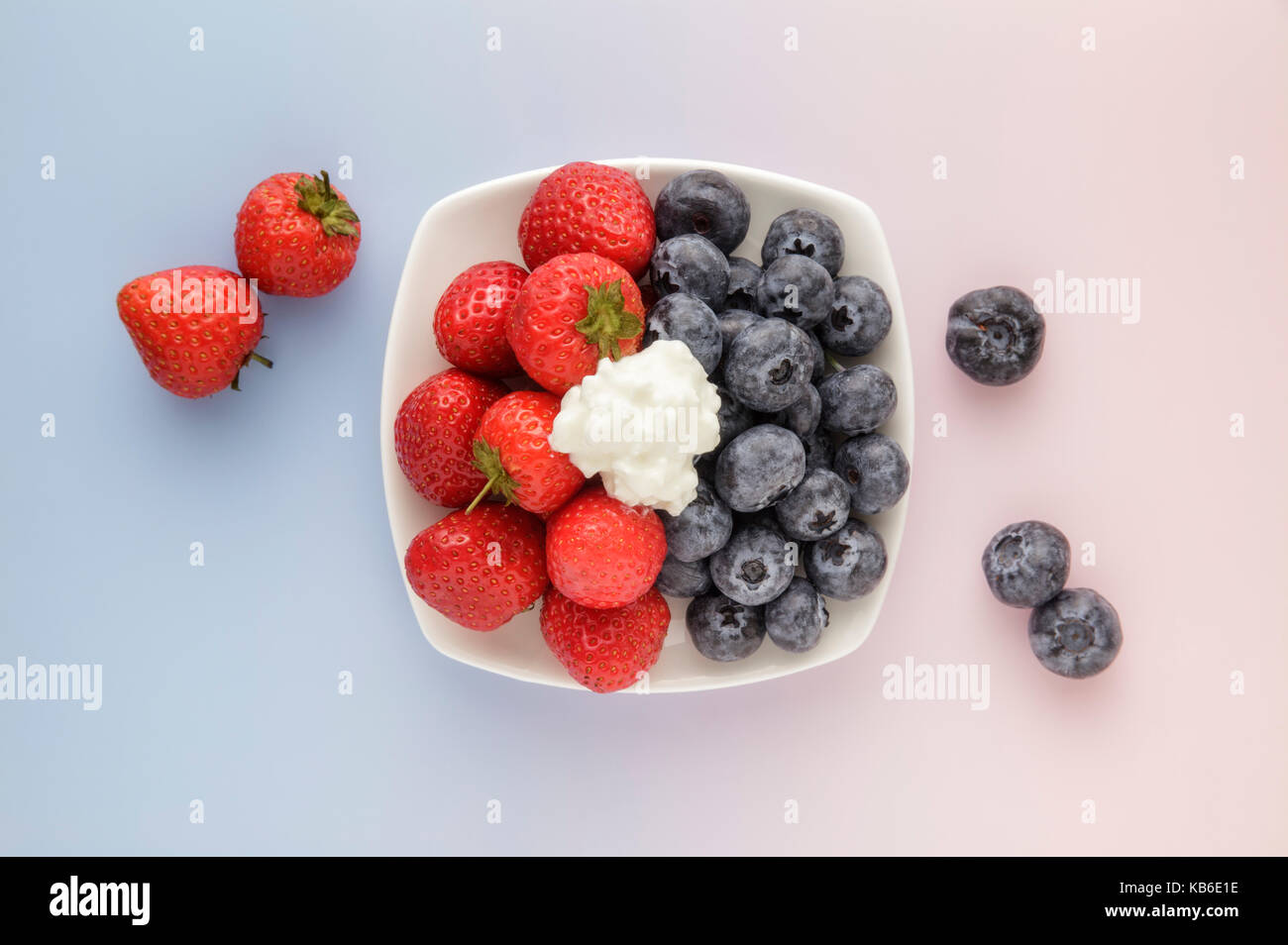 Erdbeeren und Blaubeeren auf Rosa und blauen Hintergrund Stockfoto