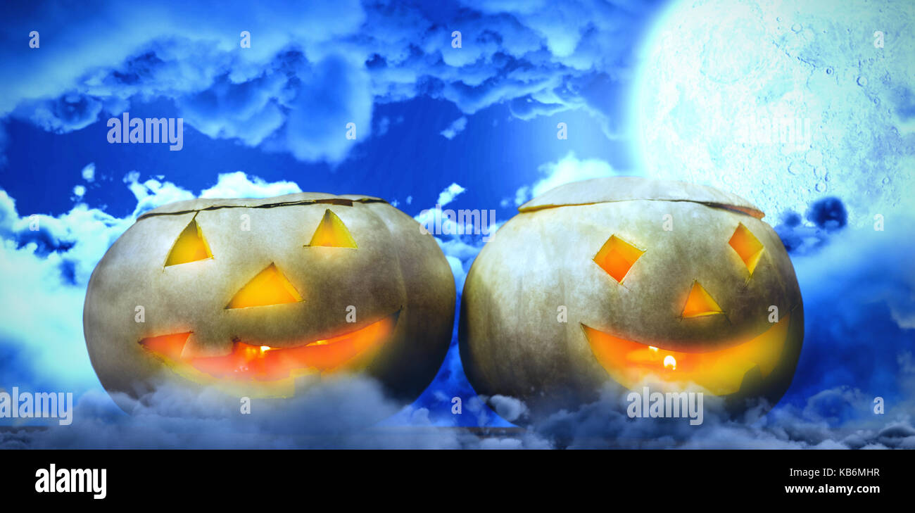 Beleuchtete jack o Laternen auf Tisch gegen Moon shining zwischen Clouds Stockfoto