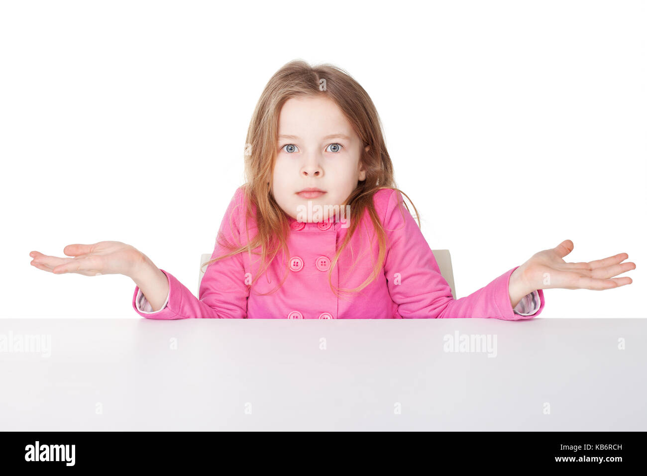 Süße kleine Mädchen im roten Hemd zuckte mit den Schultern, beim Sitzen am Tisch auf weißem Hintergrund Stockfoto