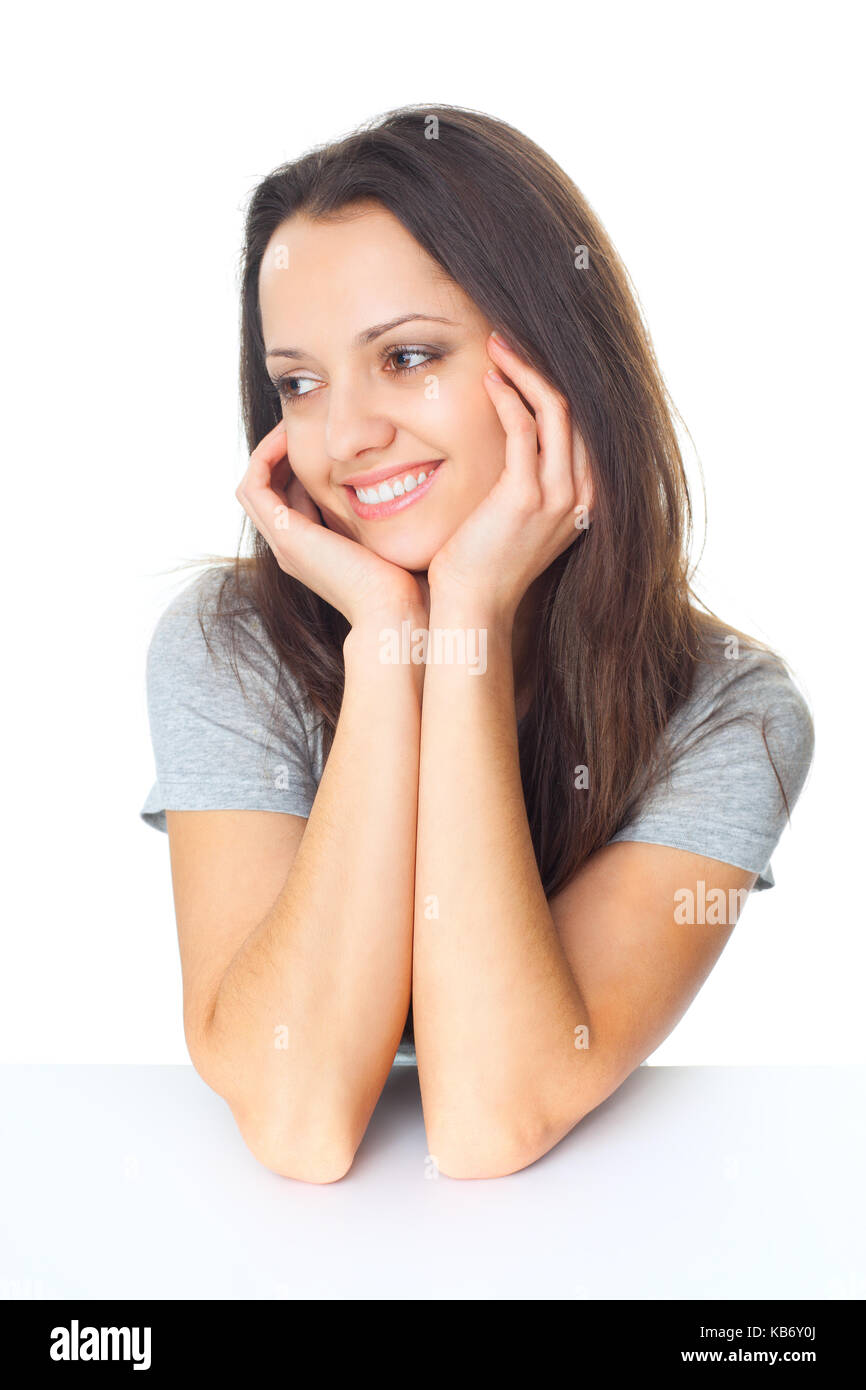 Porträt der hübsche junge brünette Frau mit den Ellenbogen auf den Tisch und das Kinn auf die Hände auf weißem Hintergrund isoliert auf der Grundlage Stockfoto