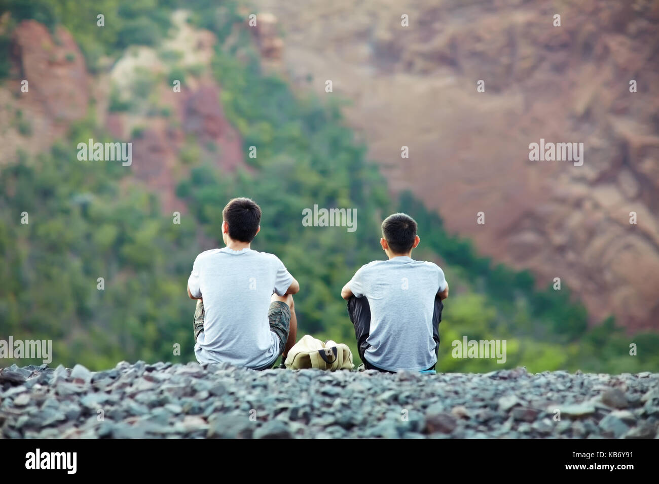 Zwei touristische junge Männer sitzen auf der felsigen Steilküste und genießen Sie einen wunderschönen Blick Stockfoto