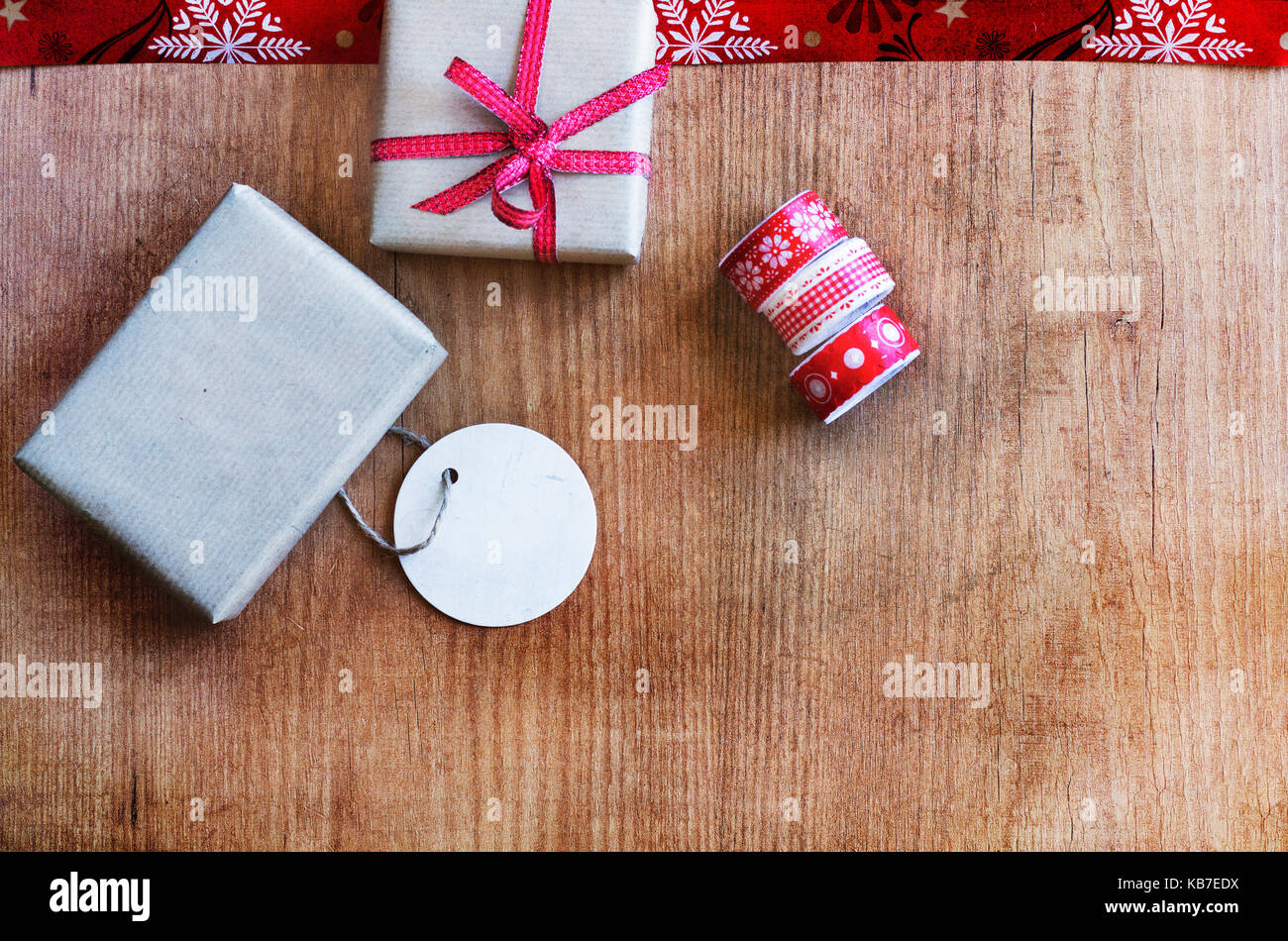 Rustikal, Geschenke mit roten Bändern, Grußkarte und Klebeband auf Holz Hintergrund. Kopieren Sie Raum. Vorbehaltlich gegen weiche Fenster Beleuchtung erfasst. Stockfoto