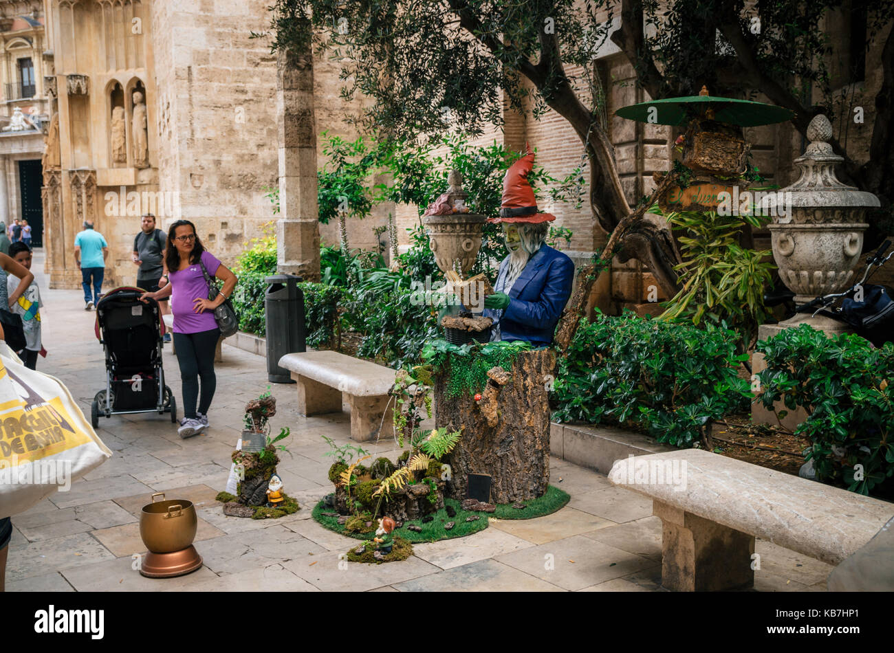 Valencia, Spanien - Juni 3, 2017: lebende Statue eines Mannes in leuchtenden Farben lackiert und Stumpf mit Springbrunnen auf der Straße sitzt. Stockfoto