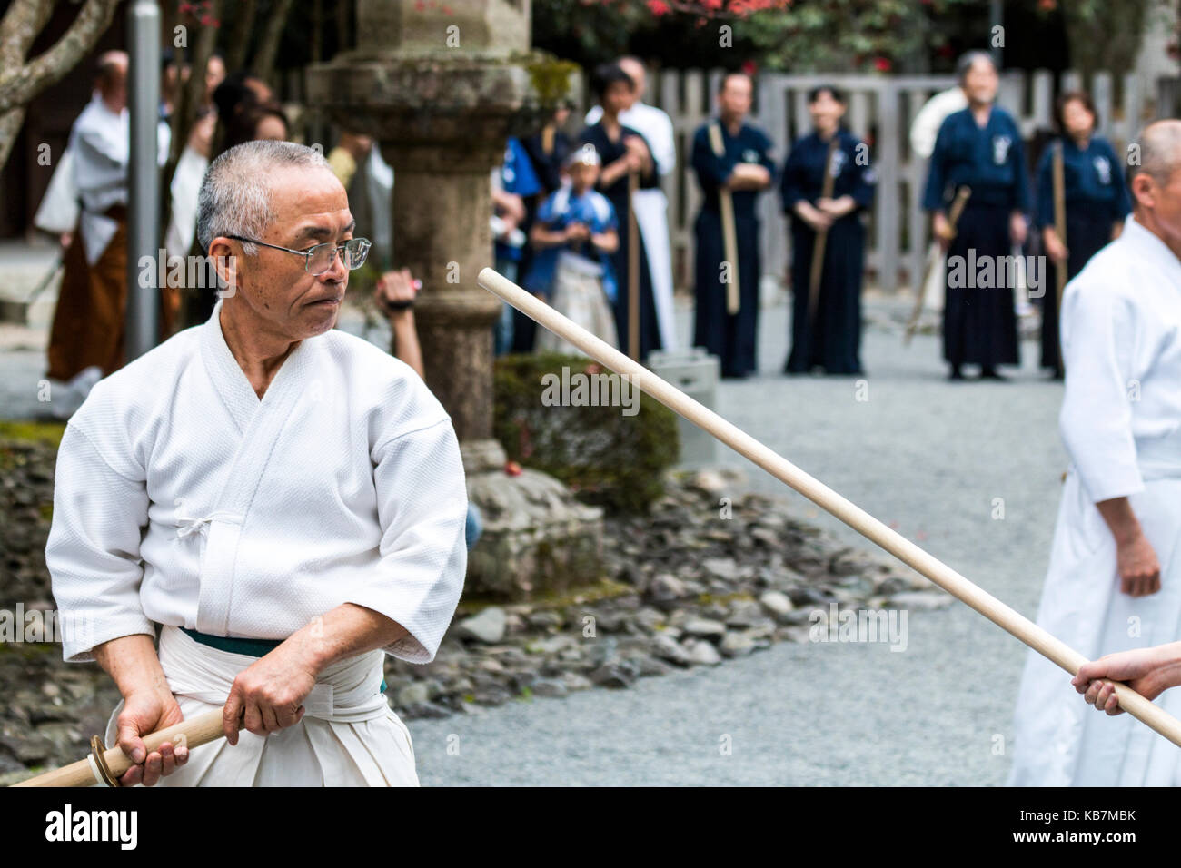 Japanische Master swordsman, reifer Mann, weiß Training mit bokken oder bokuto gekleidet, Holz- Samurai Schwert, Tada Schrein. Genji Festival. Stockfoto