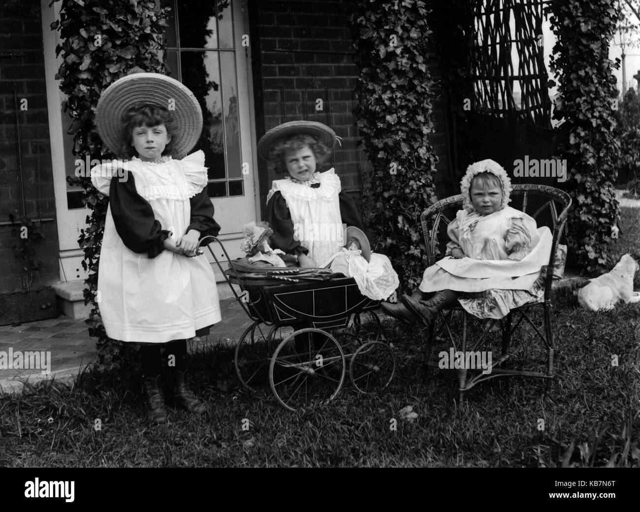 AJAXNETPHOTO. 1890 - 1914 (ca.). Ort unbekannt. - Drei KLEINE MÄDCHEN POSIEREN FÜR DIE KAMERA IN EINEM CARDEN MIT PUPPEN IN EINEM SPIELZEUG KINDERWAGEN UND HUND. Fotograf: unbekannt © DIGITAL IMAGE COPYRIGHT AJAX VINTAGE BILDARCHIV QUELLE: AJAX VINTAGE BILDARCHIV SAMMLUNG REF: AVL 172109 3 Stockfoto