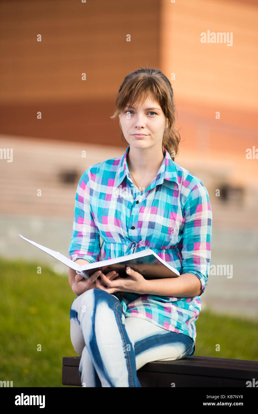 Studentin mit Copybook auf Bank. Sommer-Campus-Park. Stockfoto