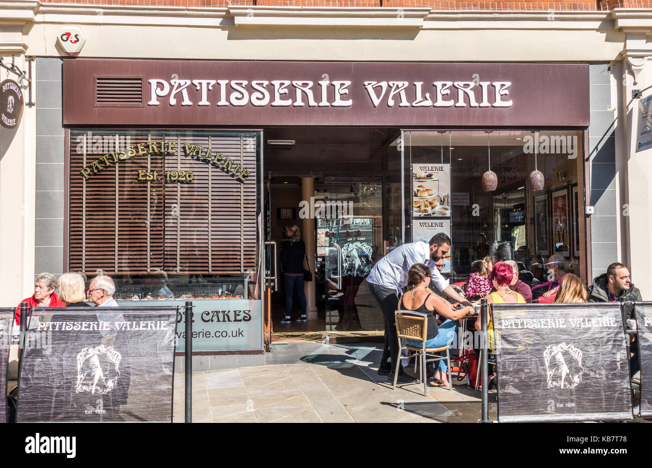 Mann sitzend Kunden im warmen Sonnenschein an Patisserie Valerie Cafe bietet, Cathedral Square, das Stadtzentrum von Peterborough, Cambridgeshire, England, UK. Stockfoto