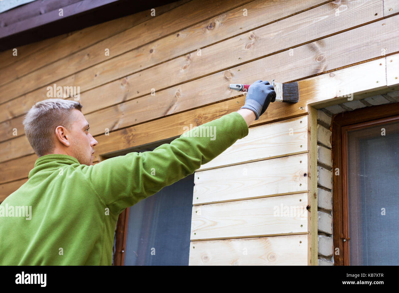 Maler mit Pinsel malen Haus Holzfassade Stockfoto