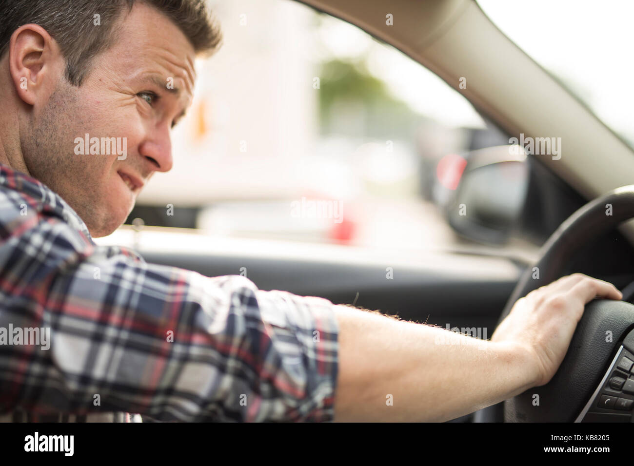 Junger Mann, der ein Auto fährt irritiert. Irritierte Fahrer Stockfoto