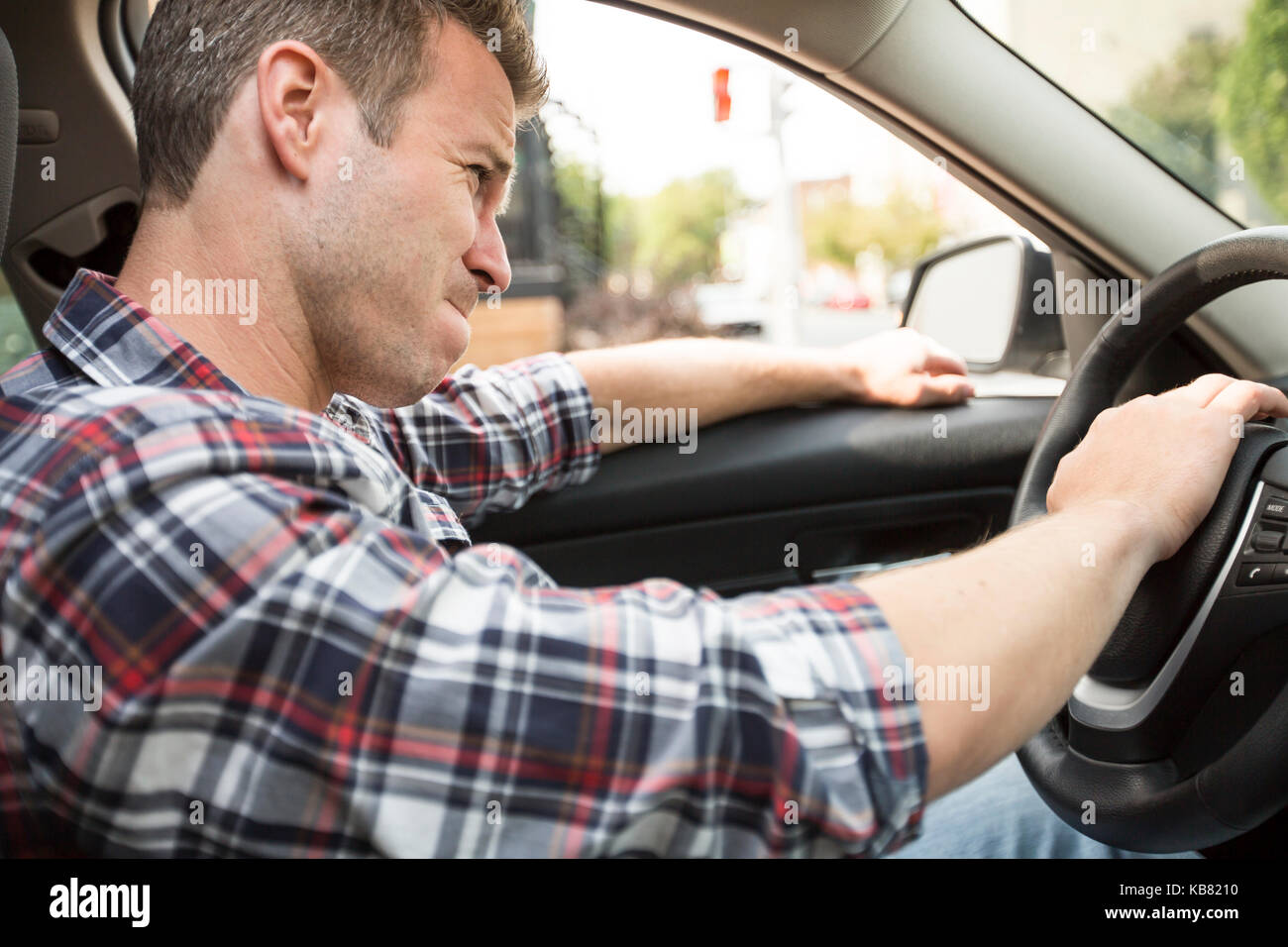 Junger Mann, der ein Auto fährt irritiert. Irritierte Fahrer Stockfoto