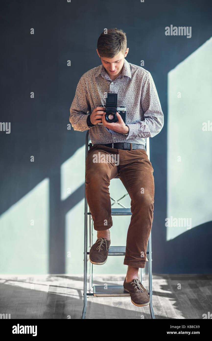 Portrait von stattlicher Mann mit retro Mitte Kamera im Studio. Fotograf Stockfoto