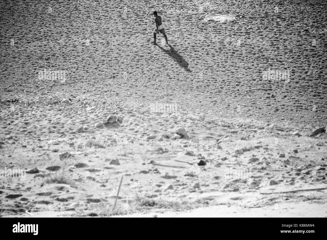 Ein Mann zu Fuß den Strand ist wie ein Schatten auf dem Sand Stockfoto