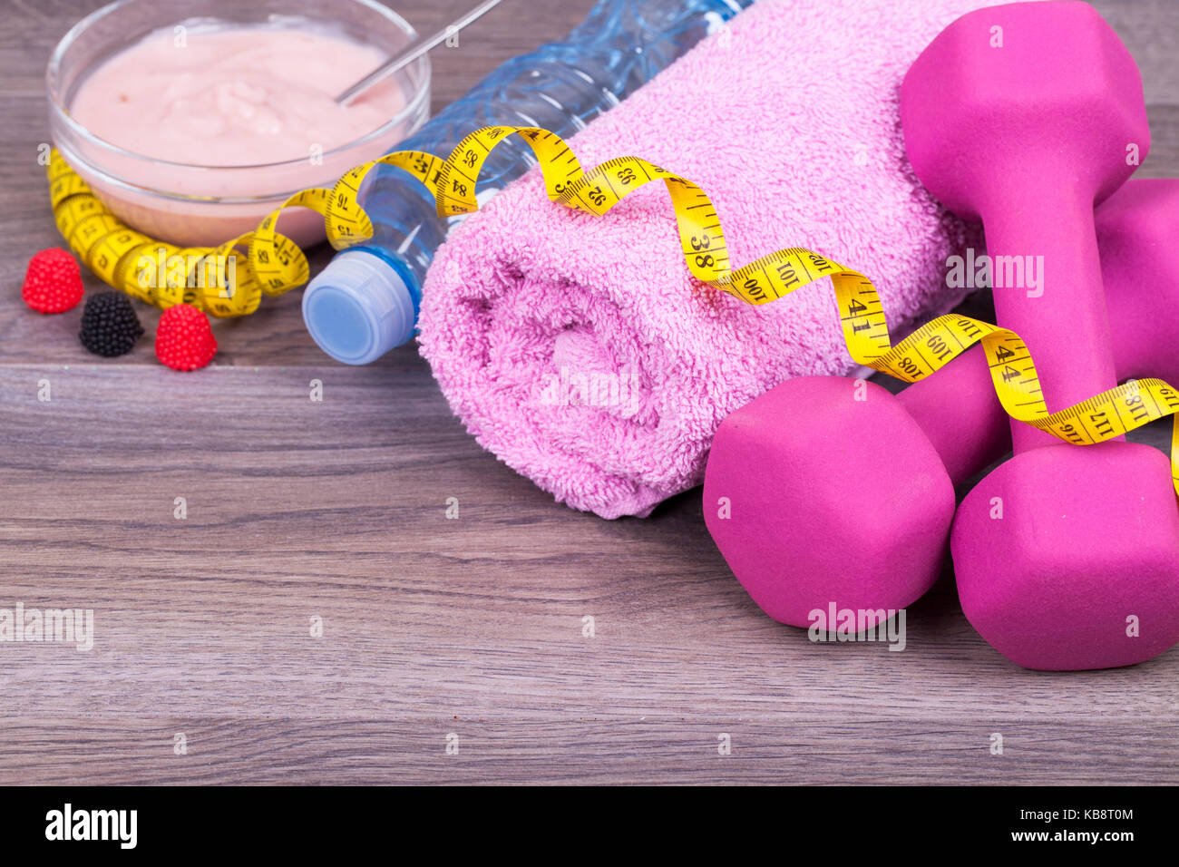 Fitness eine Diät Konzept mit einer Flasche Wasser, Gewichte, Handtuch, Apple und sehr leckeres Obst Joghurt auf einer hölzernen Hintergrund. Mit leeren Platz für Ihren Text Stockfoto