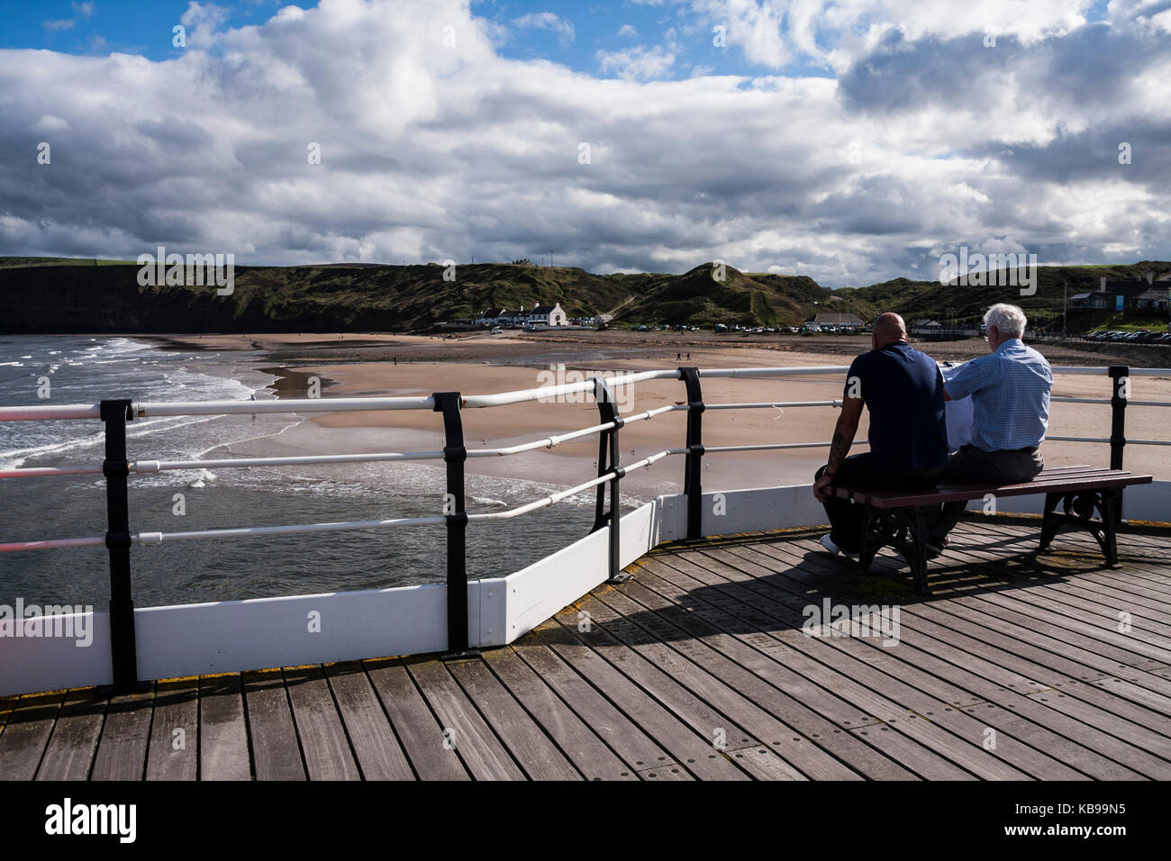 Zwei Männer saßen auf einer Bank auf dem Pier in Saltburn am Meer, England, Großbritannien Stockfoto