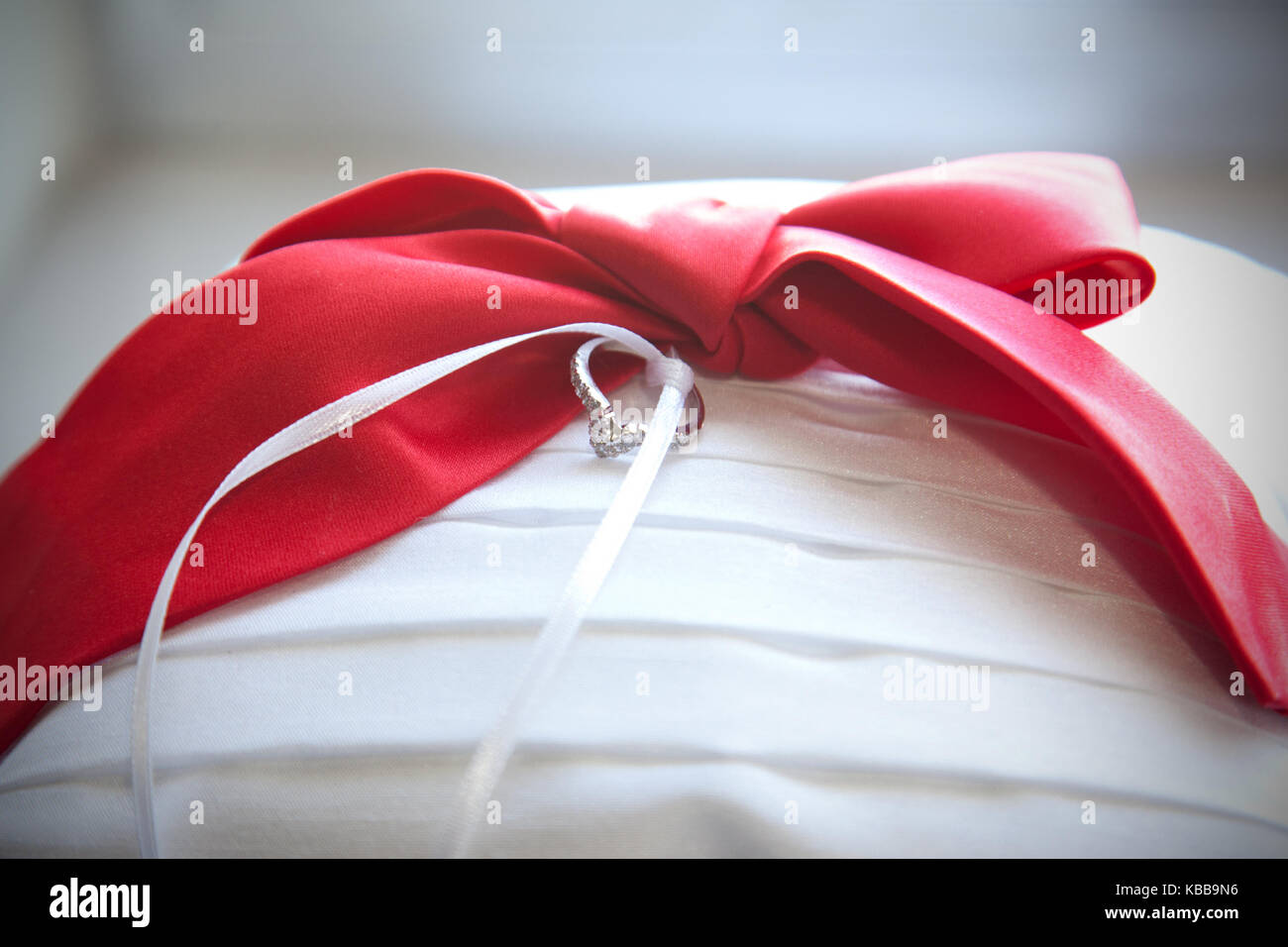 Ein glitzerndes Silber und Diamanten Hochzeit Ring auf einem Ring bearer Kissen mit Red Ribbon Stockfoto