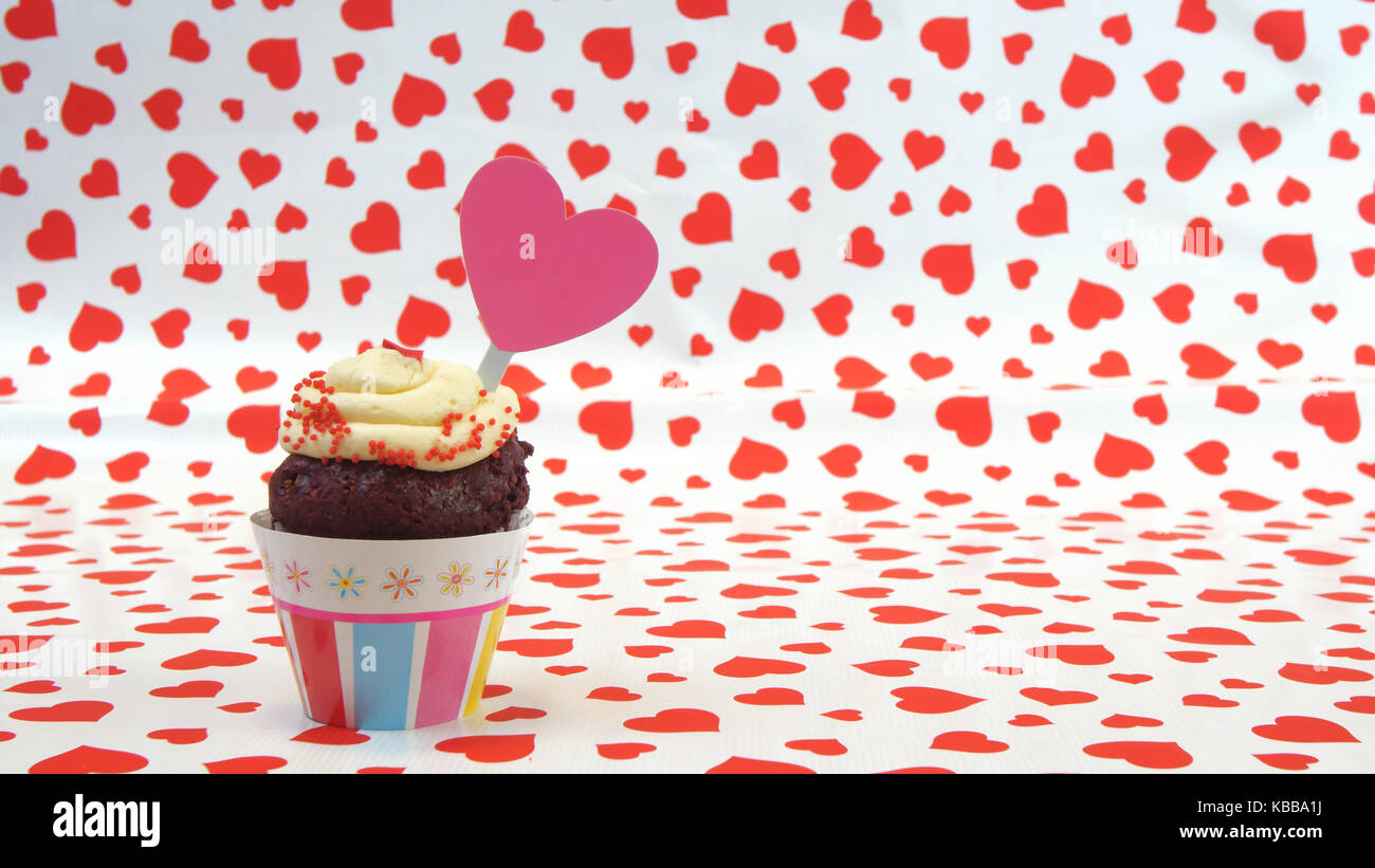 Schokolade Kuchen mit Sahne und Herzförmigen Schild auf roten Herzen Hintergrund Stockfoto