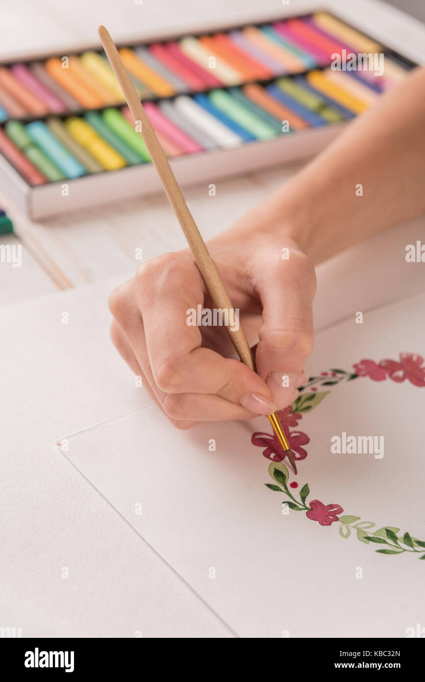 Junge Künstler zeichnen Blumen muster mit Aquarellfarbe und Pinsel auf Papier am Arbeitsplatz Stockfoto