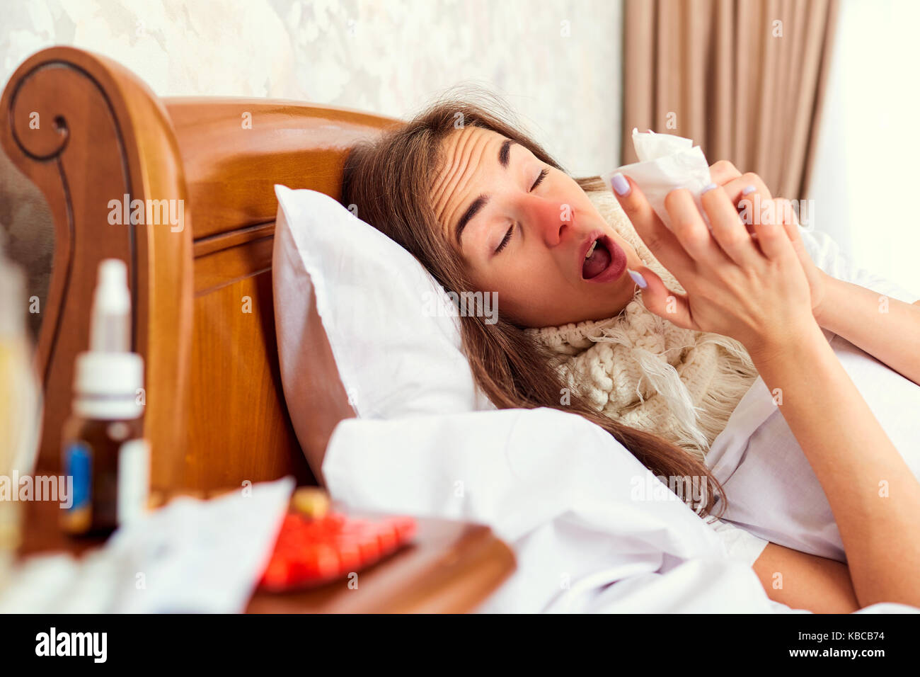 Ein krankes Mädchen liegt Niesen auf dem Bett. Stockfoto