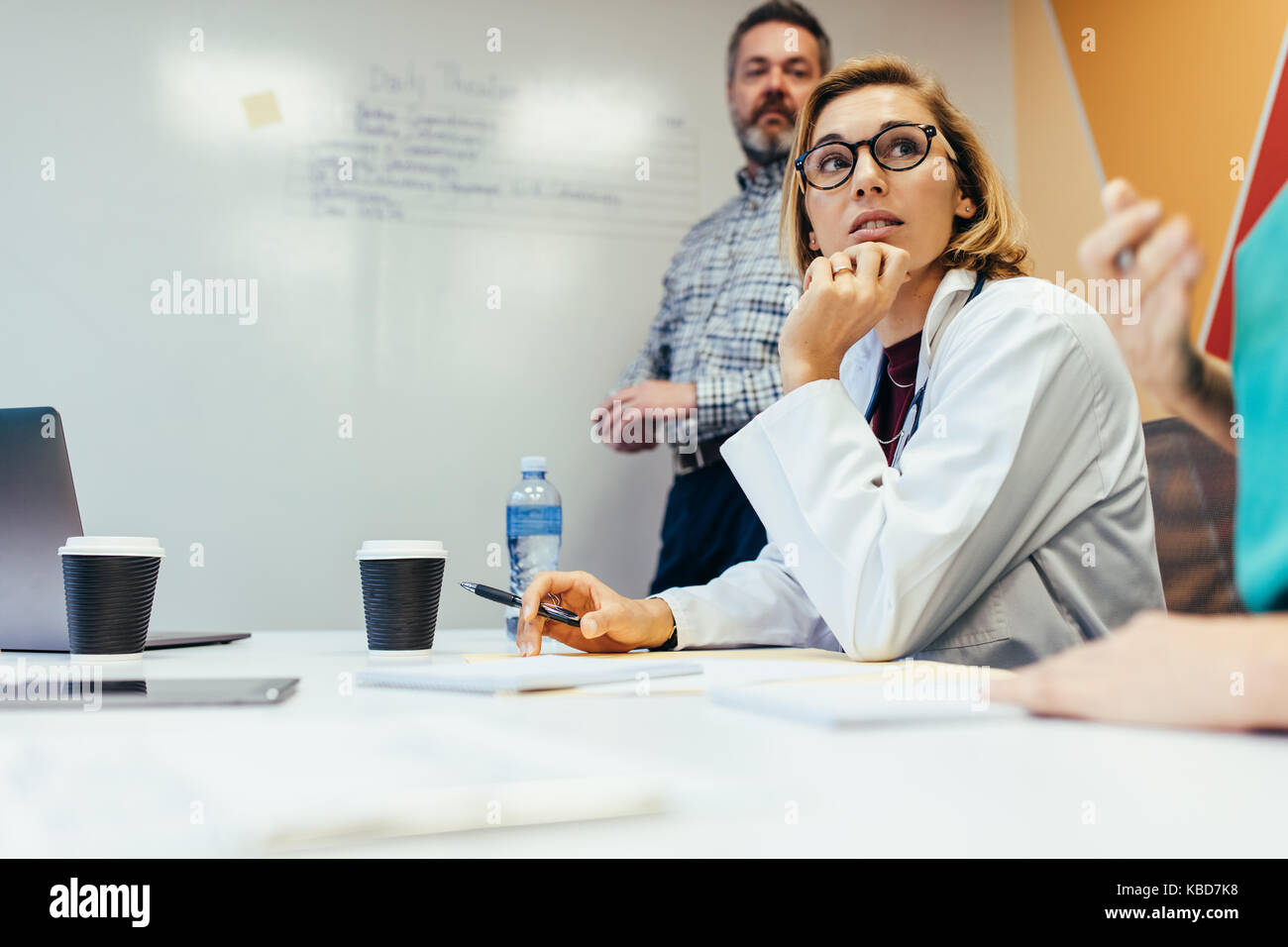 Team von medizinischen Fachleuten diskutieren während der Sitzung im Sitzungssaal. Frau Doktor in der Besprechung am Krankenhaus. Stockfoto