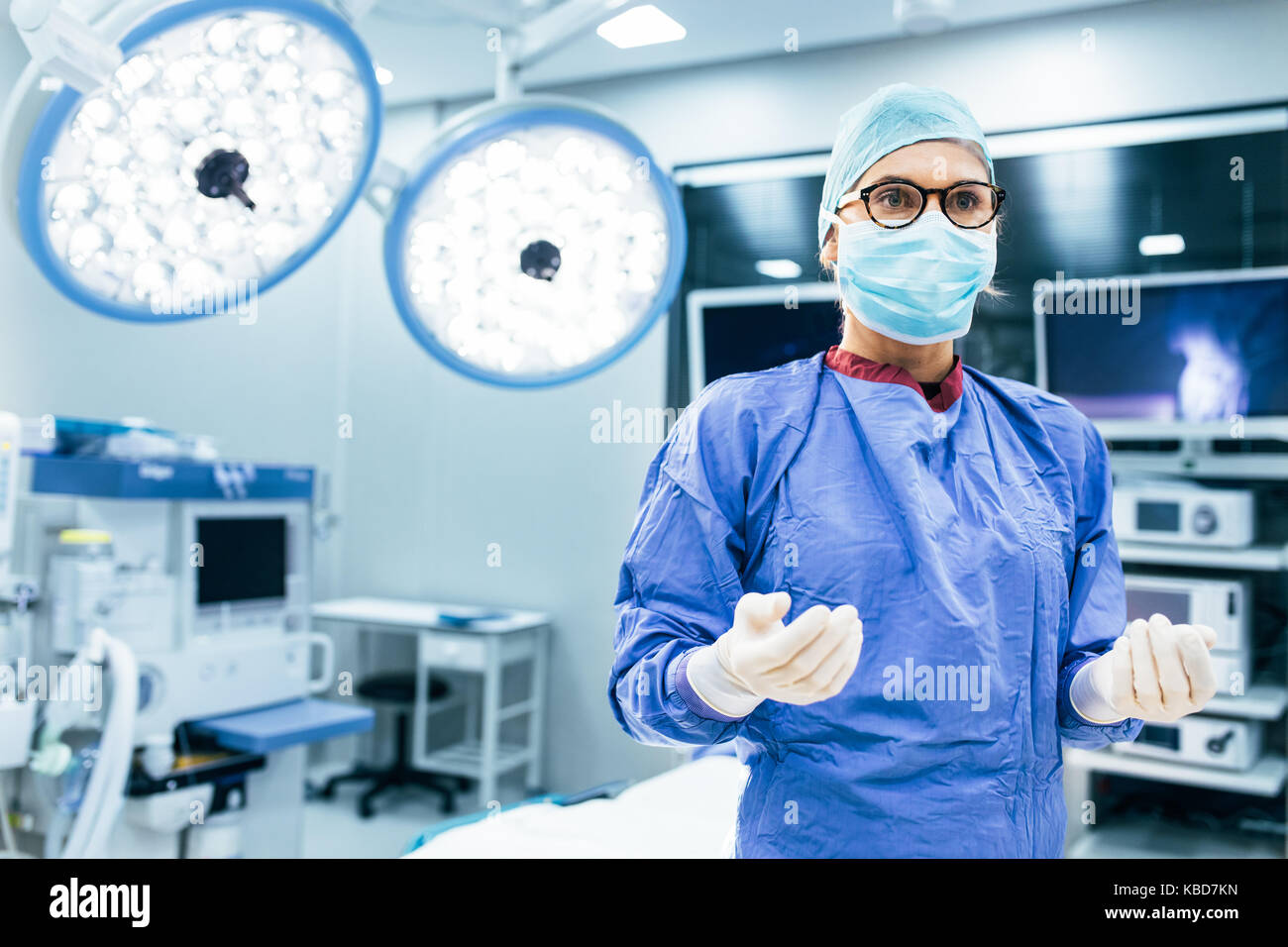 Portrait von weiblichen Chirurg in chirurgischen Einheitliche in Betrieb Theater entfernt. Arzt in Scrubs und medizinische Maske im modernen Krankenhaus Op. Stockfoto