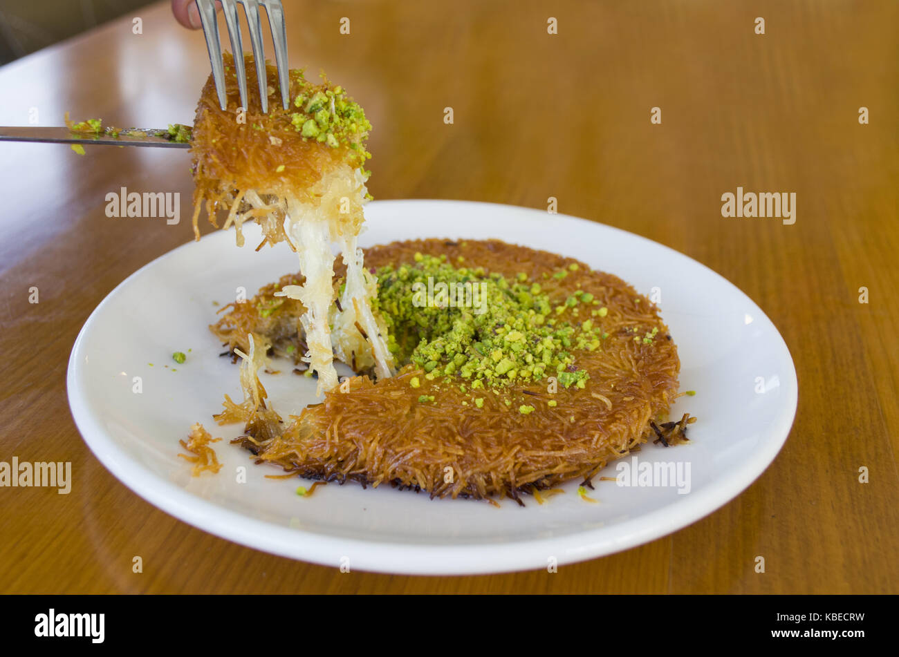 Türkisches Dessert kunefe, kunafa, kadayif mit Pistazien Pulver und Käse heiß gegessen ein süßes Stockfoto