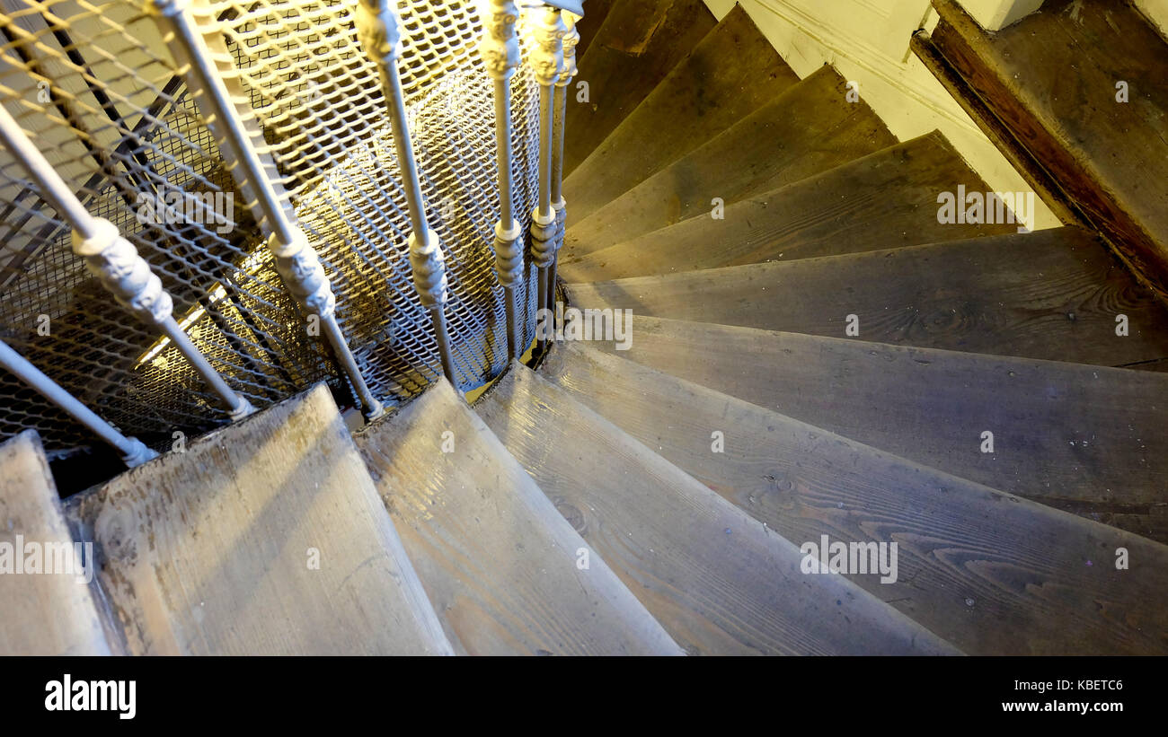 Eine hölzerne Treppe mit Metallschienen Spirale nach unten Stockfoto