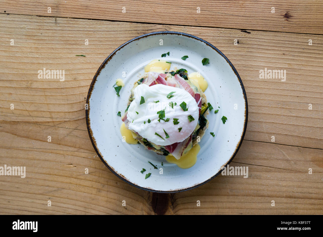 Rustikale leckere Eier Benedikt auf Platte auf hölzernen Tisch Stockfoto